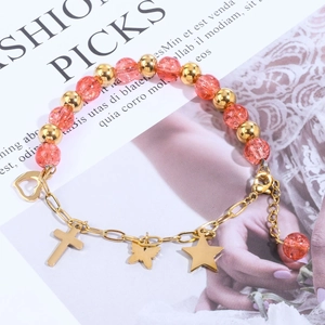 Detail of beaded bracelet with pink crystal beads and gold heart cross charms on magazine