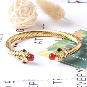 Dettaglio del bracciale rigido dorato a treccia con pietre preziose e cristalli intarsiati
