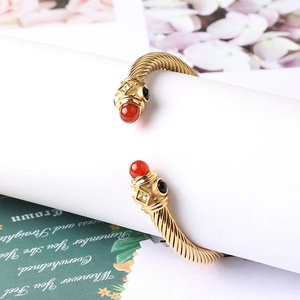 Dettaglio del bracciale rigido a treccia dorata con agata rossa e gemma nera intarsiata