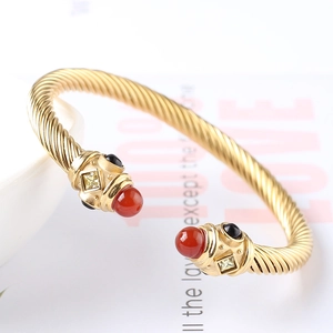 Dettaglio del bracciale rigido a corda con intarsi di pietre preziose e finitura dorata