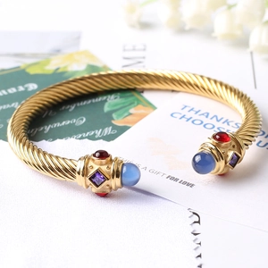 Dettaglio di un bracciale a cavo dorato con gemme colorate incastonate e stile vintage