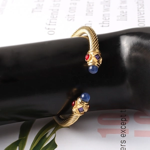 Dettaglio macro del bracciale a cavo ritorto dorato con pietre preziose colorate incastonate