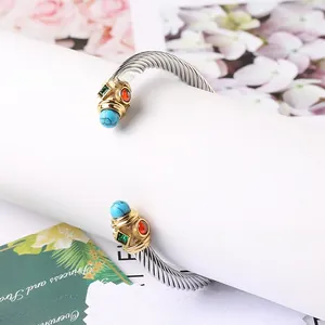 Dettaglio macro del bracciale a cavo d'argento con punte dorate e pietre preziose