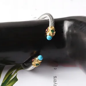 Dettaglio del bracciale a cavo in acciaio inossidabile con pietre colorate e terminali dorati