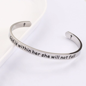 Detailed macro of silver stainless steel cuff featuring God is within her engraving