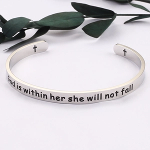 Detail of engraved inspirational quote and cross symbol on polished stainless steel cuff