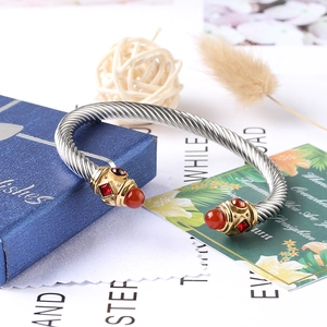 Vista macro del bracciale a cavo ritorto argento con punte oro e gemme rosse