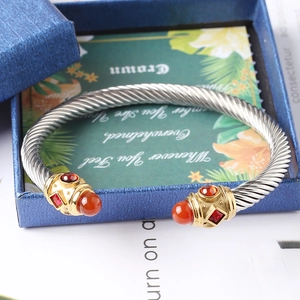 Dettaglio del bracciale a cavo intrecciato con gemme rosse su una confezione regalo