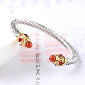 Dettaglio bracciale rigido a cavo argento con punte dorate e pietre preziose rosse