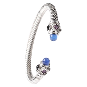 Dettaglio di un bracciale a cavo d'argento con pietre preziose blu e viola intarsiate