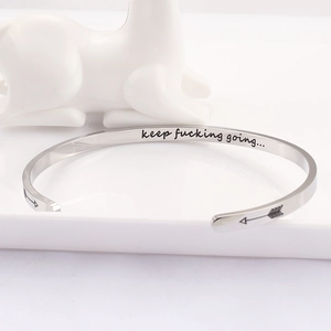 Detailed view of polished stainless steel bangle with engraved inspirational quote inside