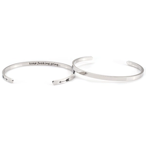 Close-up of polished stainless steel cuff with engraved motivational text and arrow icons