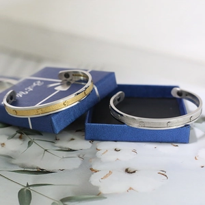 Set of gold and silver stainless steel C-shaped bracelets with clover patterns in a gift box