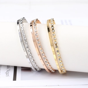 Detailed view of three-color stainless steel bangles with Roman numerals and inlaid rhinestones
