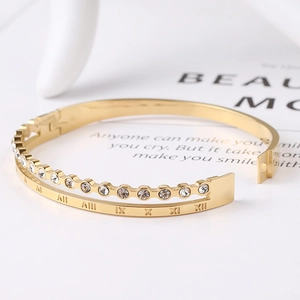 Close-up of double-layered gold bangle with Roman numerals and sparkling crystals