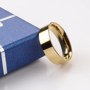 Polished 6mm golden stainless steel ring resting against a textured navy blue jewelry box