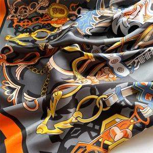 Detail of vintage silk scarf featuring golden chains and baroque patterns in orange and black