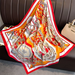 Detail of equestrian chain pattern silk scarf on brown leather background with handbag