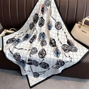 Close-up of luxury floral silk scarf with rose pattern on a leather surface