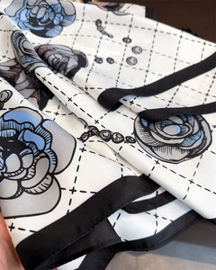 Detailed view of camellia and pearl prints on a white silk scarf with black borders