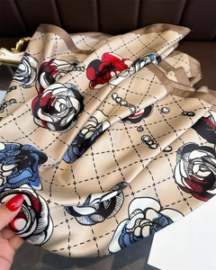 Macro detail of champagne silk scarf with red rose pattern and decorative lattice design