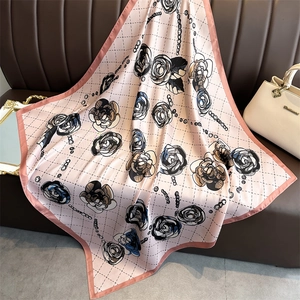 Detailed view of camellia silk scarf with chain pattern on a leather background