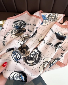 Macro detail of silk camellia floral scarf featuring smooth twill texture and hemmed edges