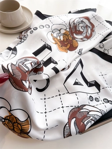 Detail of silk camellia scarf showing elegant floral patterns and artistic letters