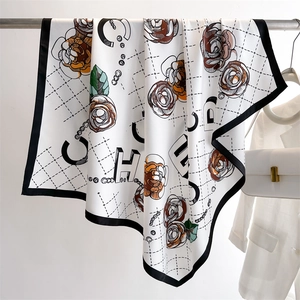 Detailed view of silk camellia scarf with black border and floral pattern on a hanger