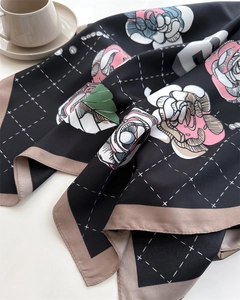 Detail of camellia silk scarf with floral print and white grid pattern on satin fabric