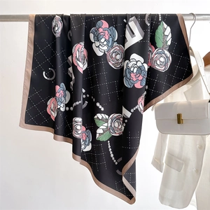 Detail of camellia floral print on a black twill silk scarf with pearl chain accents