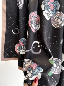 Detail of camellia flower print on black silk scarf with decorative C logo pattern