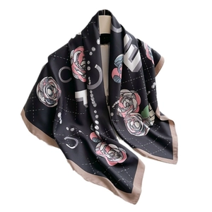 Elegant camellia silk scarf featuring floral print and geometric patterns on black silk