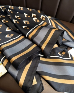 Detail view of geometric silk scarf with gold and black patterns on leather background