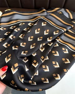 Macro shot showing the silky texture and elegant geometric patterns of the silk scarf
