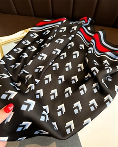 Close-up of silk scarf with light blue L-shaped patterns and striped borders