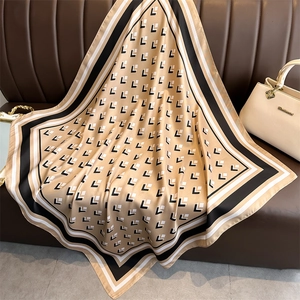 Detail of premium satin square scarf with geometric L-pattern draped on leather sofa