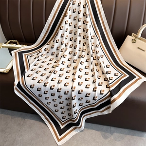 Close-up of geometric pattern silk square scarf draped on a brown leather surface