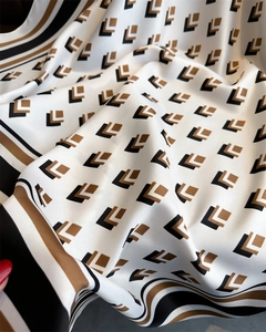 Macro shot of silk square scarf featuring black and brown geometric L-patterns and stripes