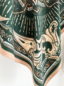 Close-up of geometric pattern on dark green silk scarf with artistic floral texture