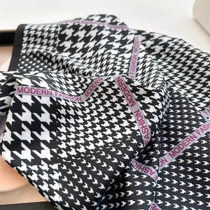 Dettaglio di sciarpa in seta pied de poule con testo Modern Fashion sul bordo