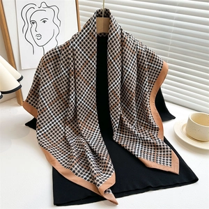 Dettaglio della sciarpa in seta con motivi pied-de-poule e geometrici su maglione nero