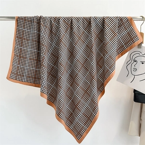 Dettaglio di sciarpa in raso pied de poule che mostra texture setosa e drappeggio elegante