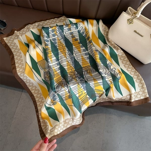 Macro detail of geometric diamond pattern silk scarf with monogram border on leather