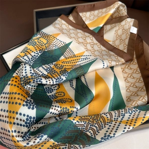 Detailed view of silk-like geometric scarf with diamond chain print and TB pattern edge