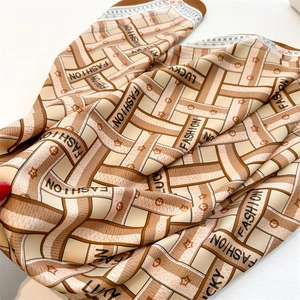 Detailed view of silk-like fashion scarf with herringbone patterns and lucky letter prints