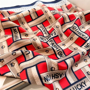 Detail of silk-like geometric pattern scarf with red herringbone print and fashion lettering