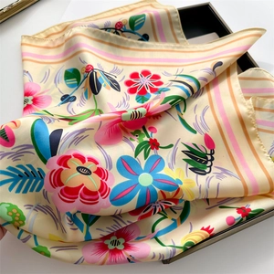 Detail of vibrant floral print scarf with soft satin texture in a black tray