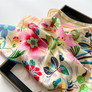 Close-up of floral silk scarf with pink dahlia print on a cream satin background