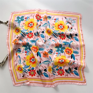 Close-up of pink silk scarf featuring vibrant yellow and orange floral patterns